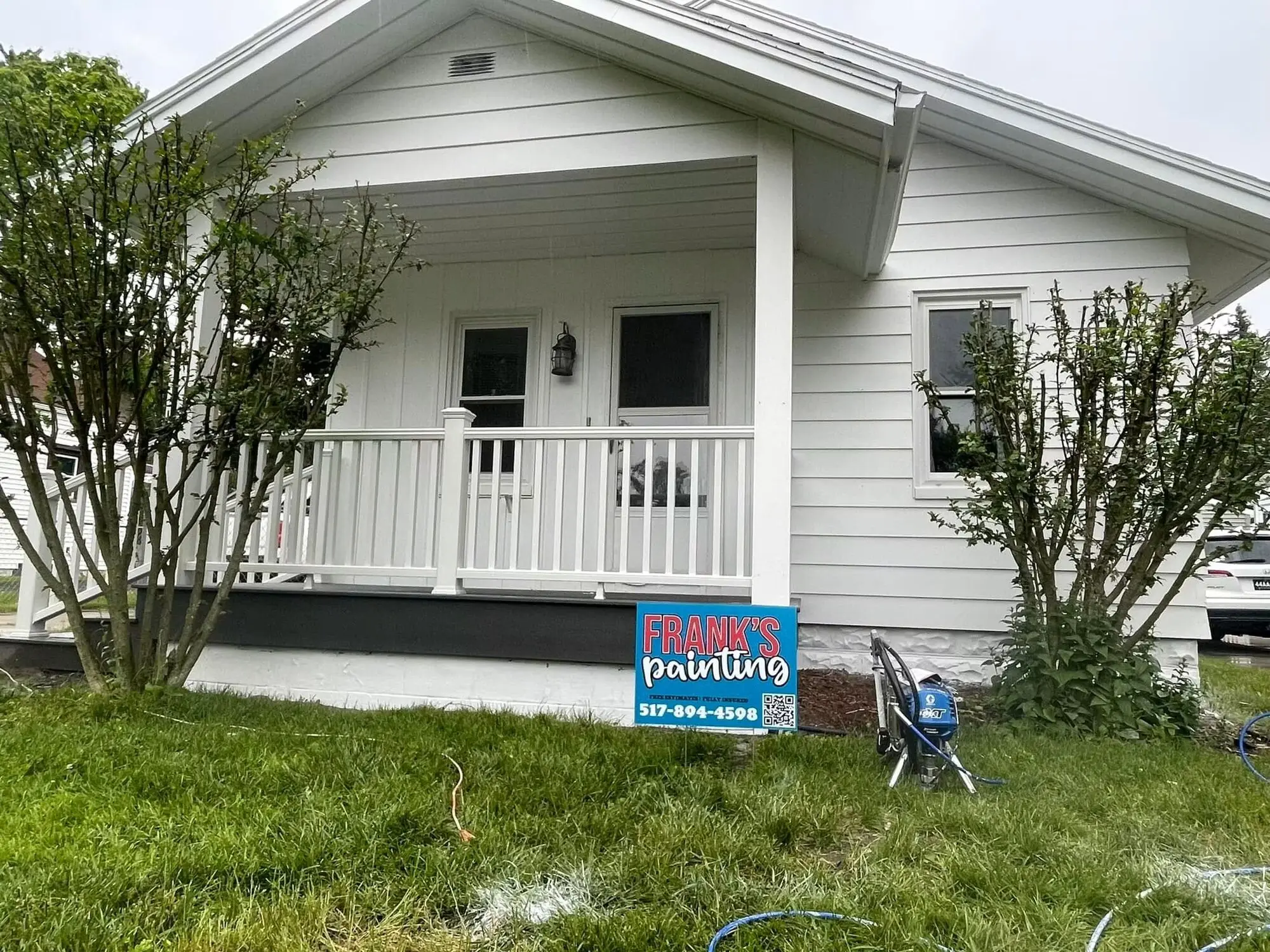 The same bungalow finished in white, with a repainted porch rail and a Frank’s Painting yard sign on the lawn