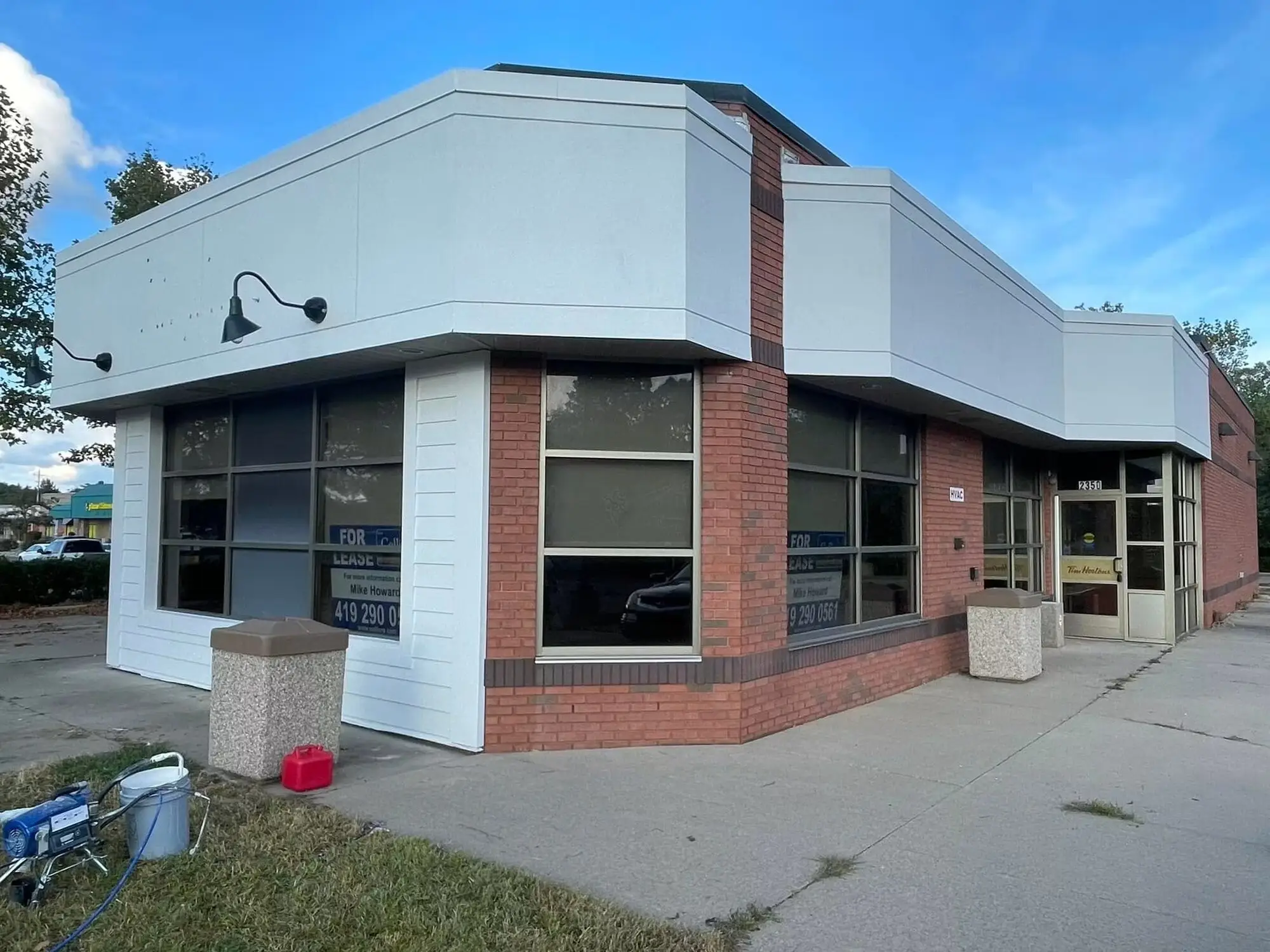 The same corner building with the upper facade repainted a clean off white above the red brick