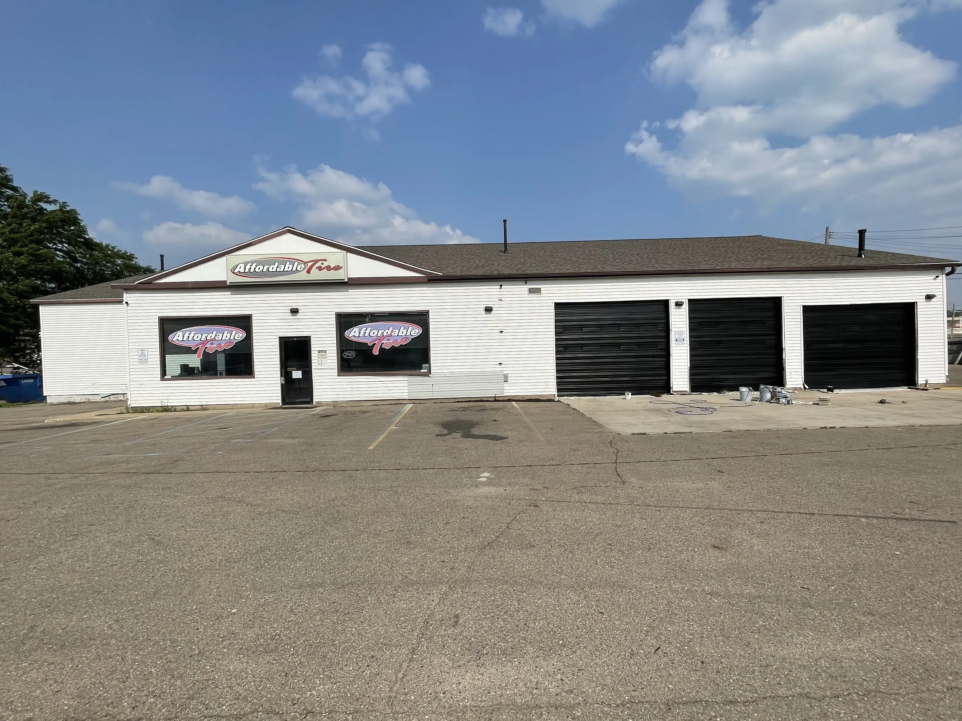 Single storey commercial building with white painted walls and four black overhead doors