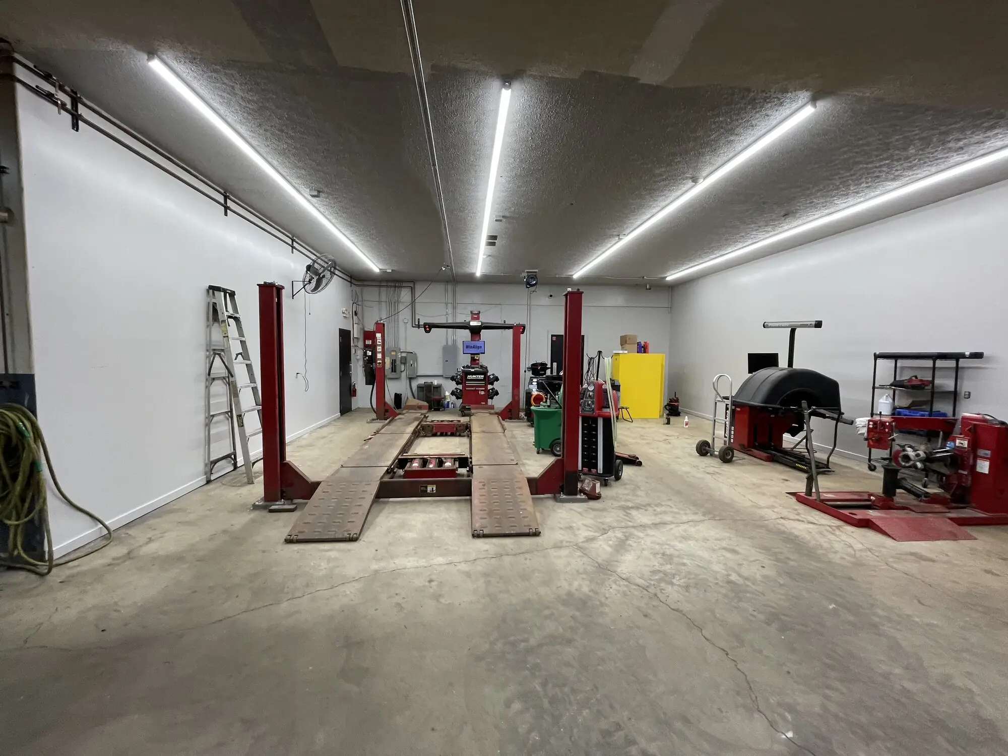 The same auto shop bay finished in white, wall and ceiling, with the lifts back in service