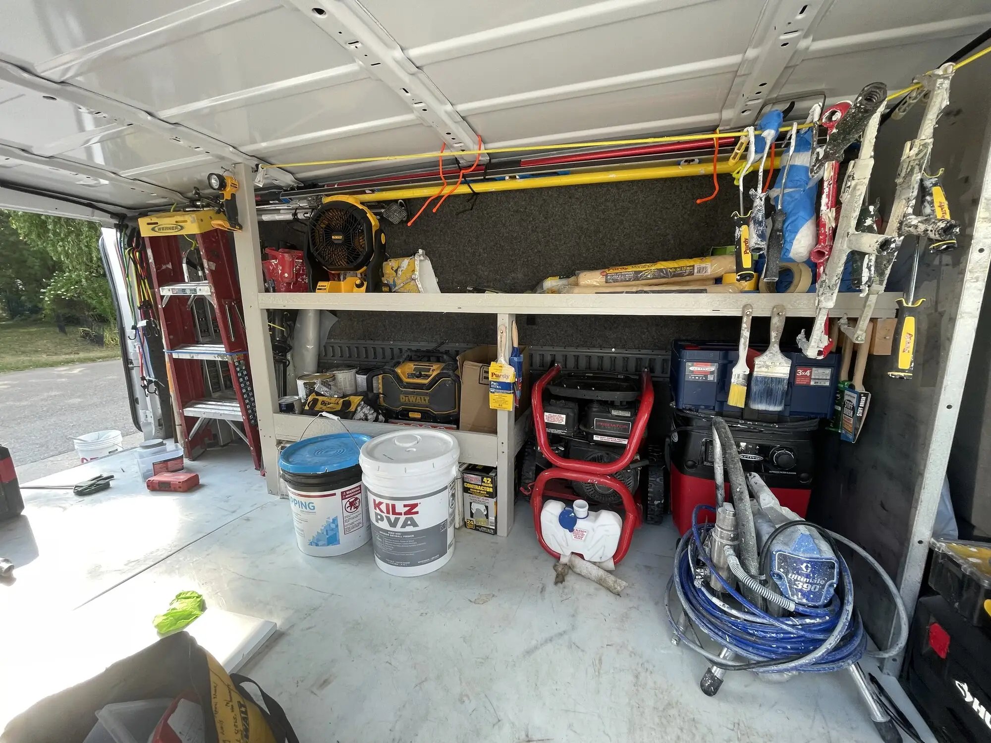 Open work trailer with sprayers, hoses, ladders and buckets racked along the wall