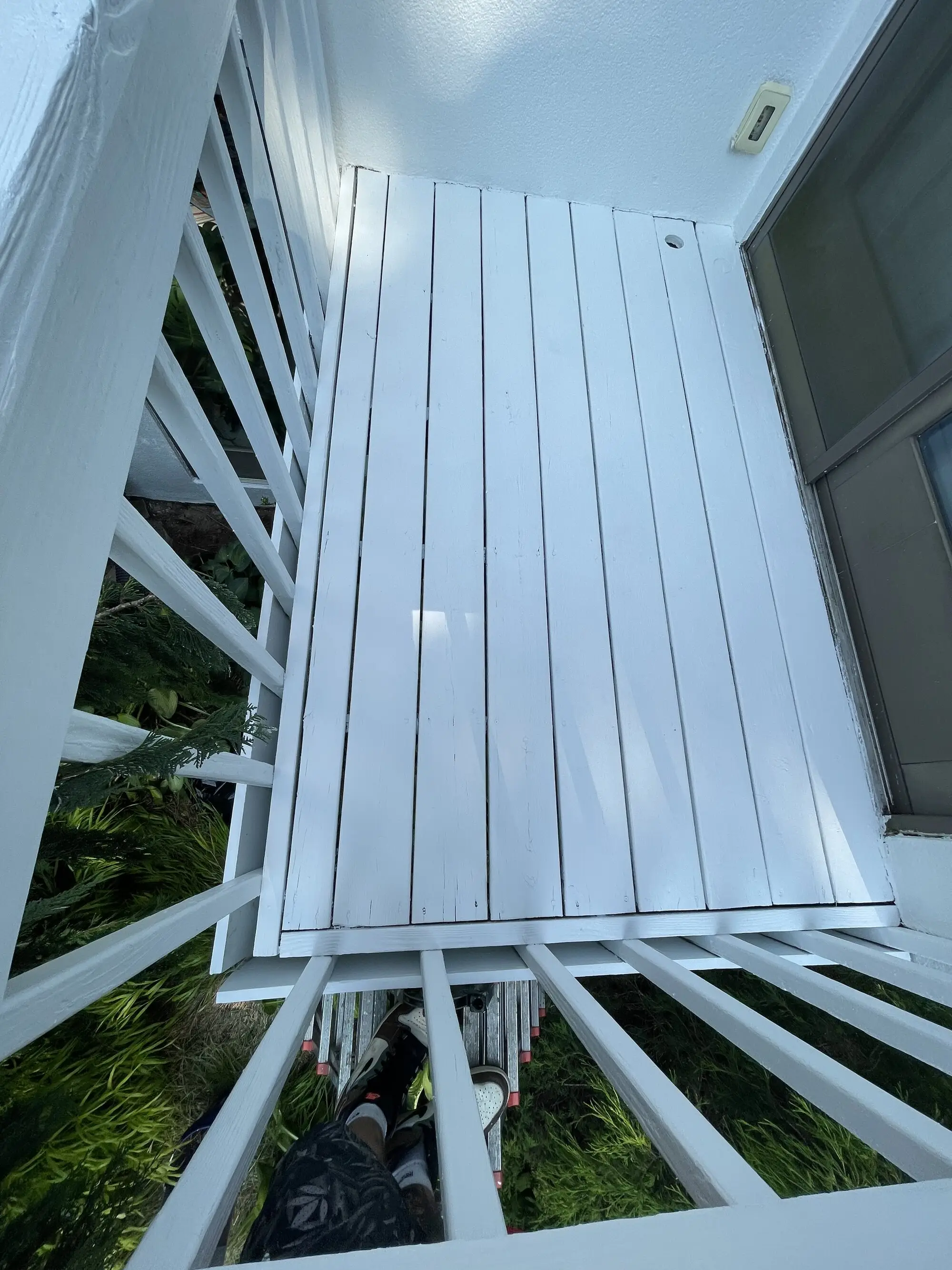 White painted deck rail and decking against a stucco wall