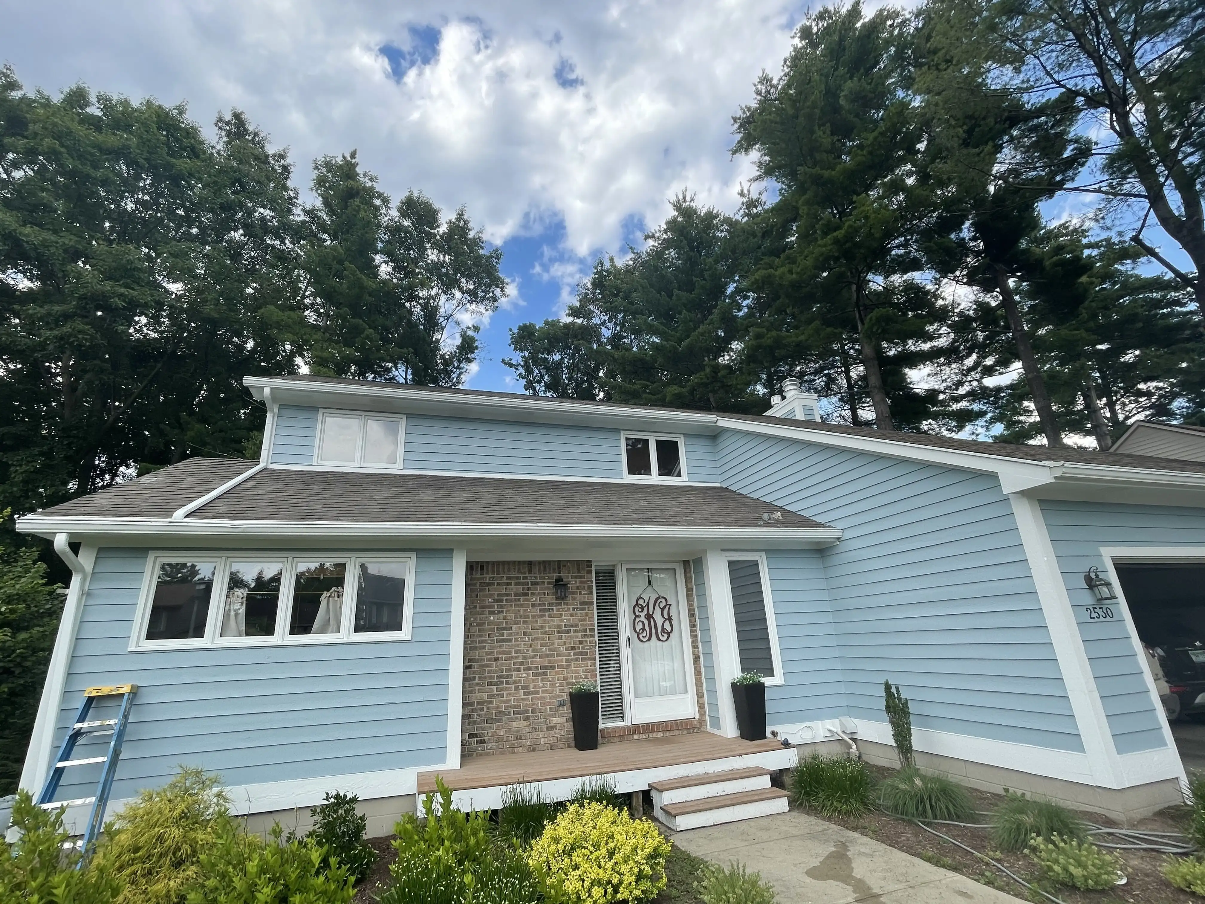 Blue split level home with white trim and a brick entry, after a full exterior repaint by Frank's Painting