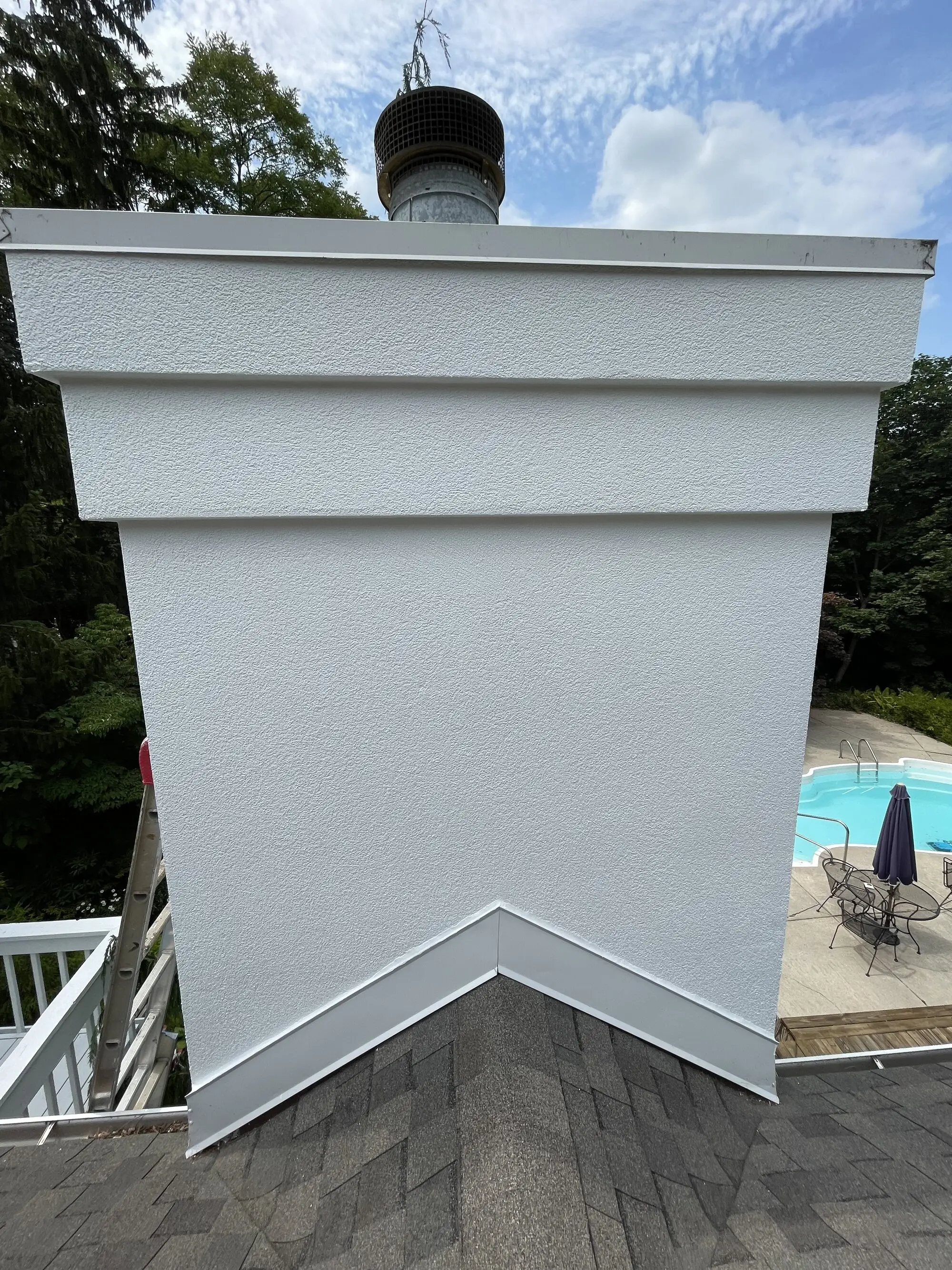 Stucco chimney finished in clean white, shot from the roof above a pool deck