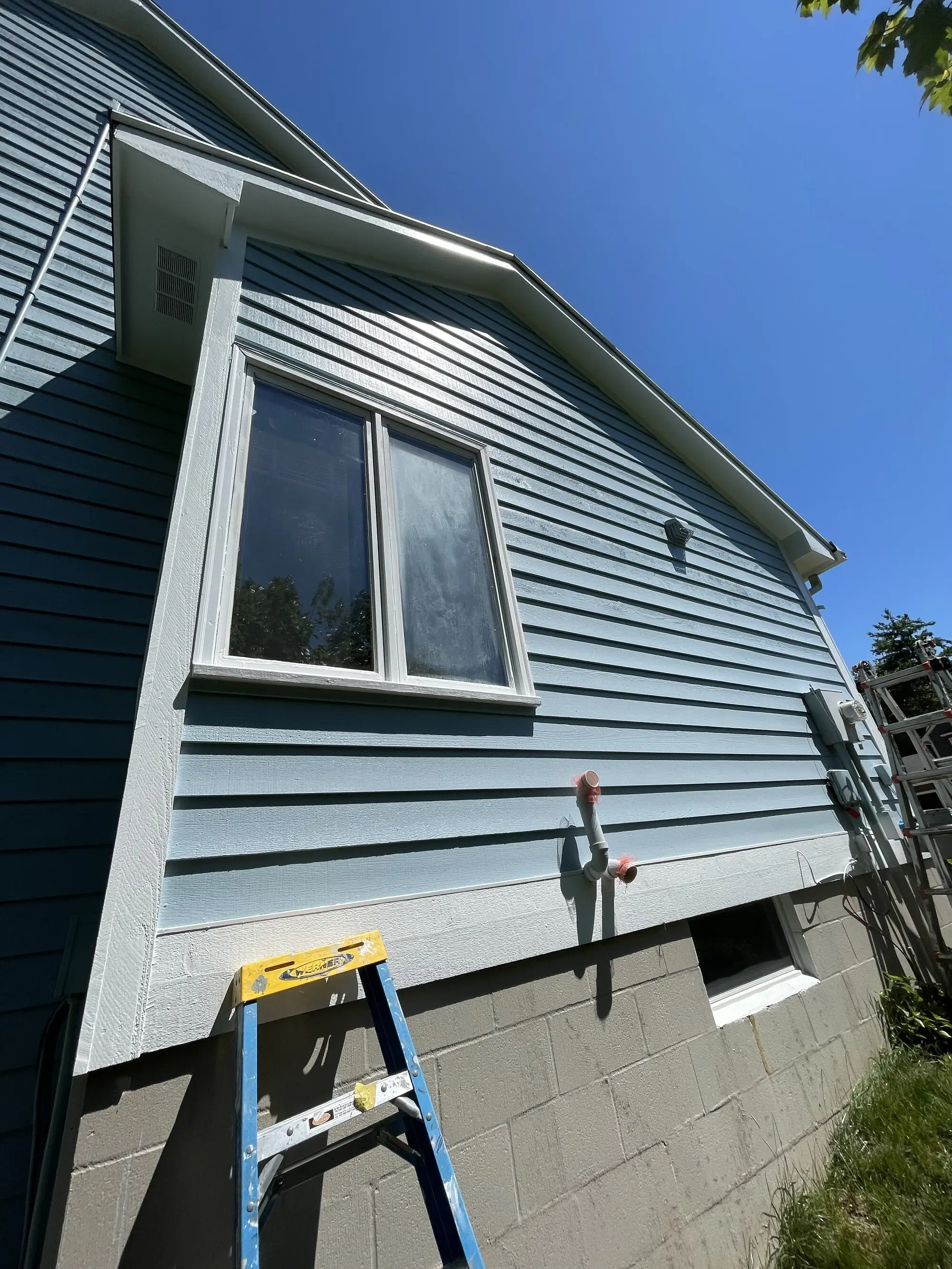 Gable end of a gray blue home with fresh white window trim