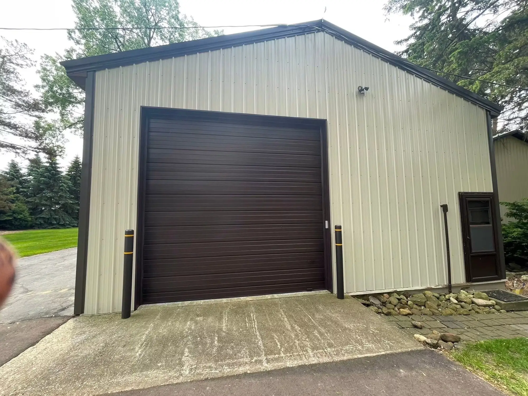 Pole barn with a repainted brown overhead door and cream metal siding