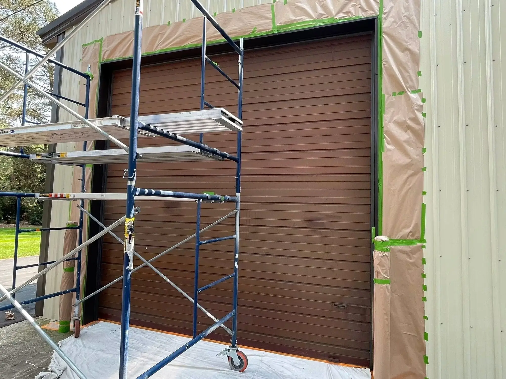 Scaffold and masking set up across a pole barn door before the coat goes on