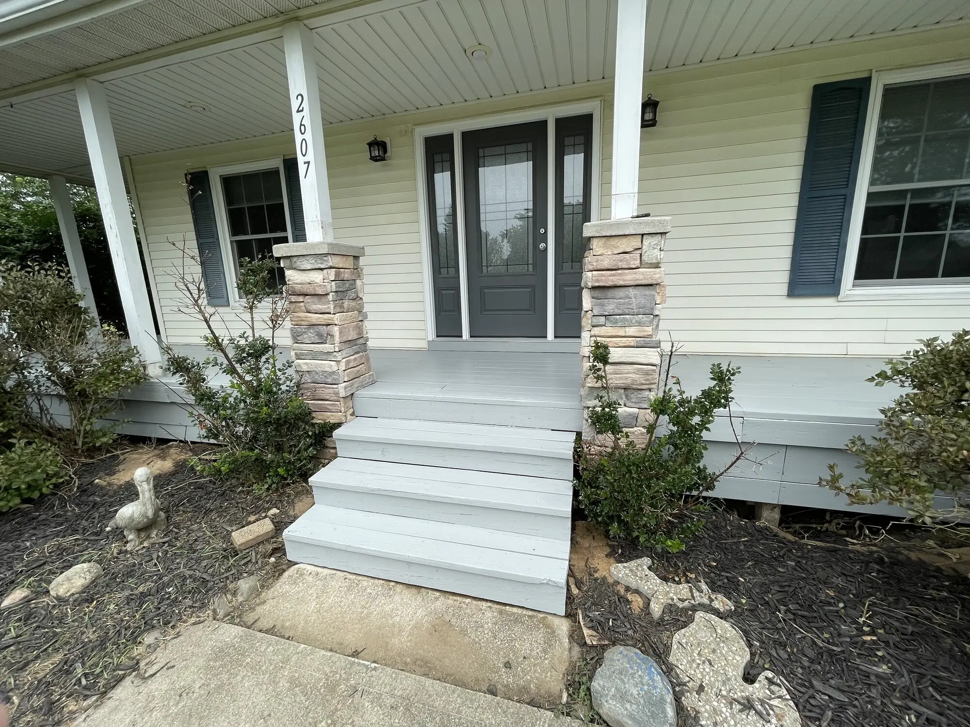 Front porch with stone column bases, freshly painted white steps and ceiling