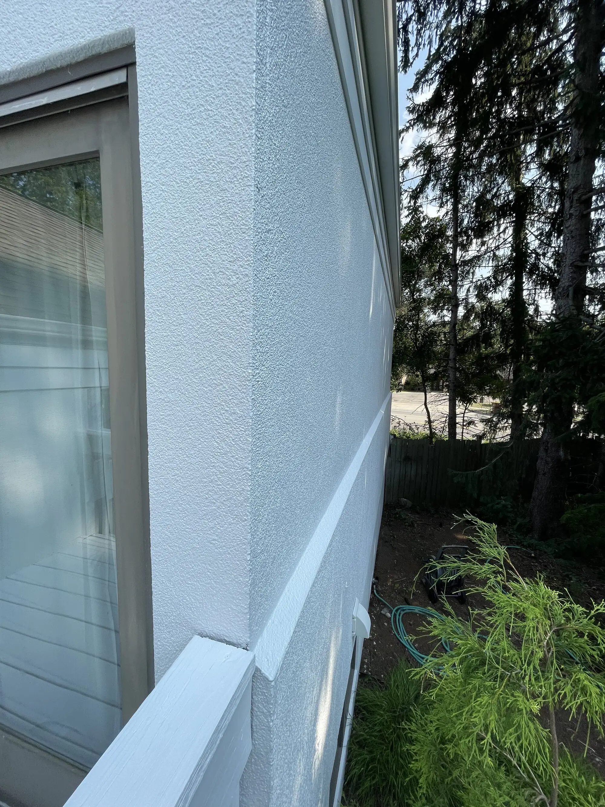 Crisp cut line where a coated stucco field meets a white painted trim band