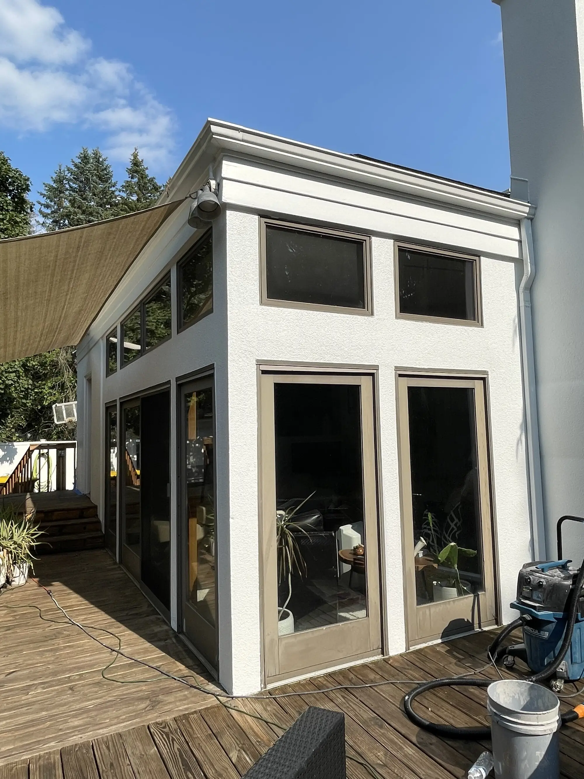 Corner of a white sunroom addition with tall windows and repainted trim