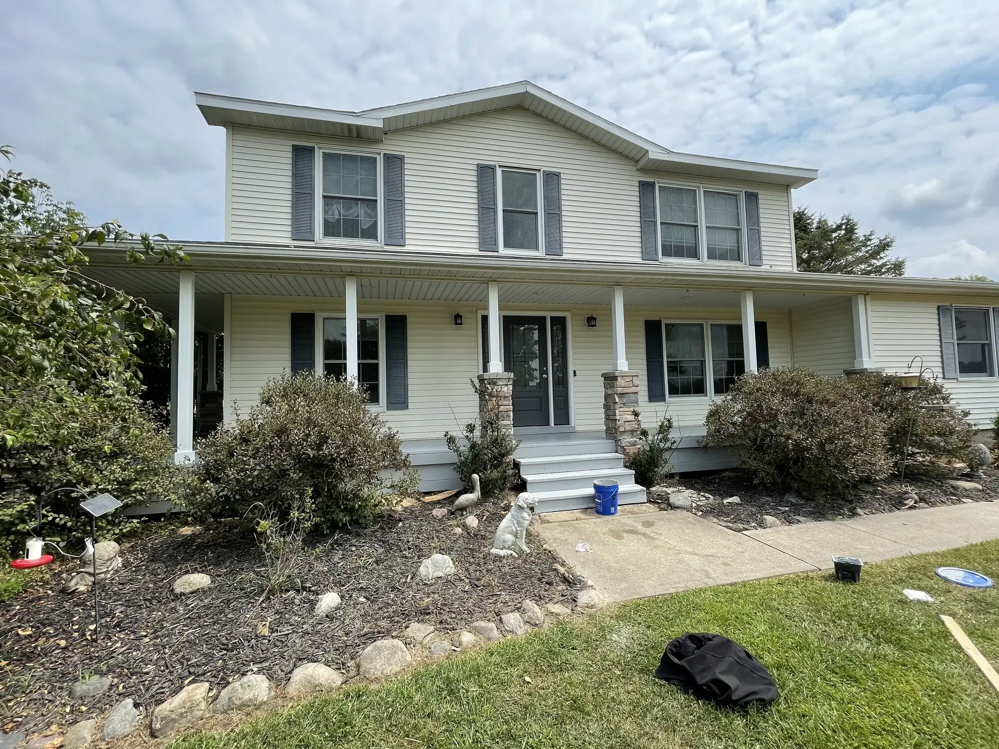 Two story home with a white covered porch and black shutters after an exterior repaint