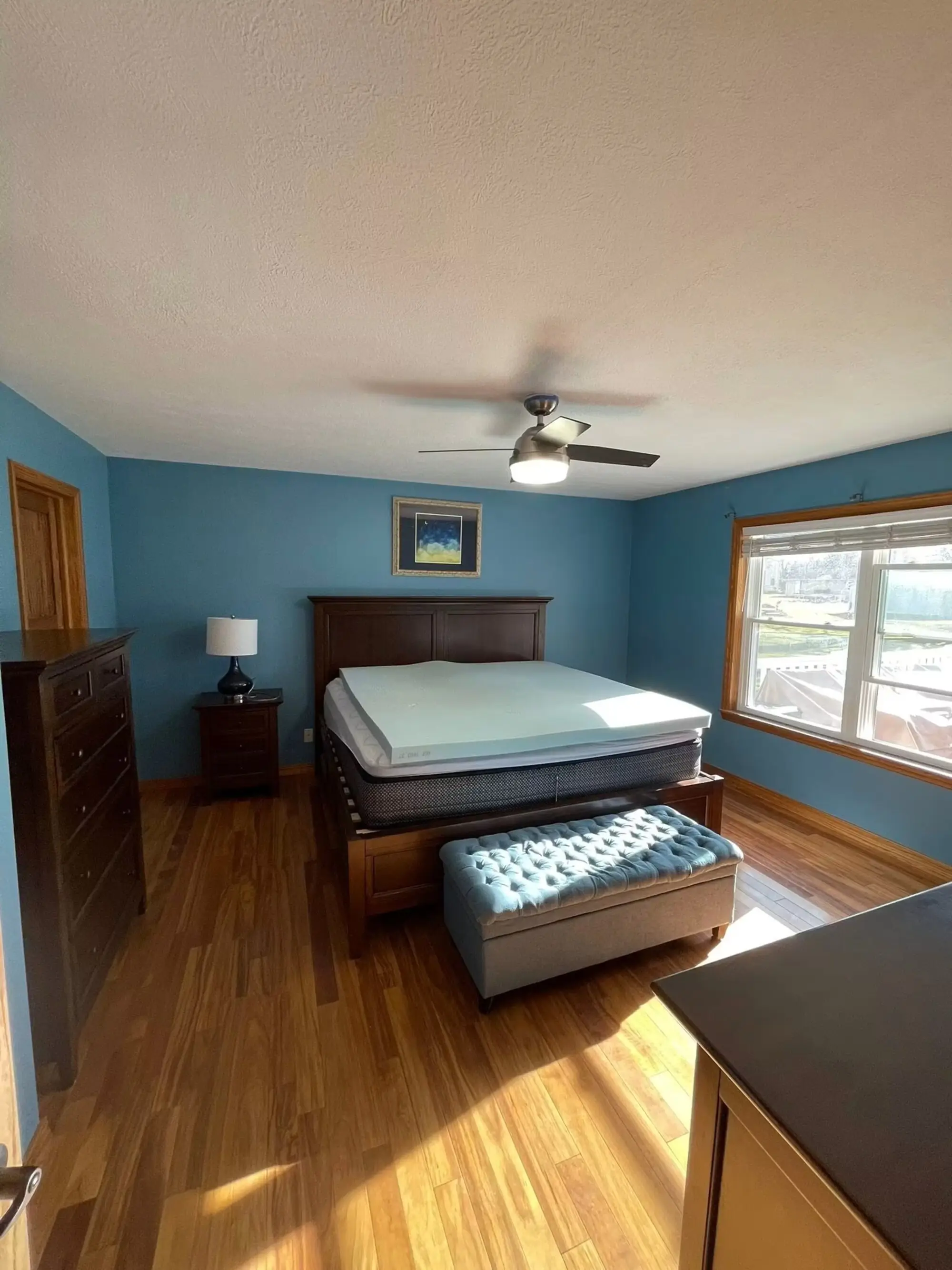 Bedroom finished in soft blue with a white ceiling and natural wood floors